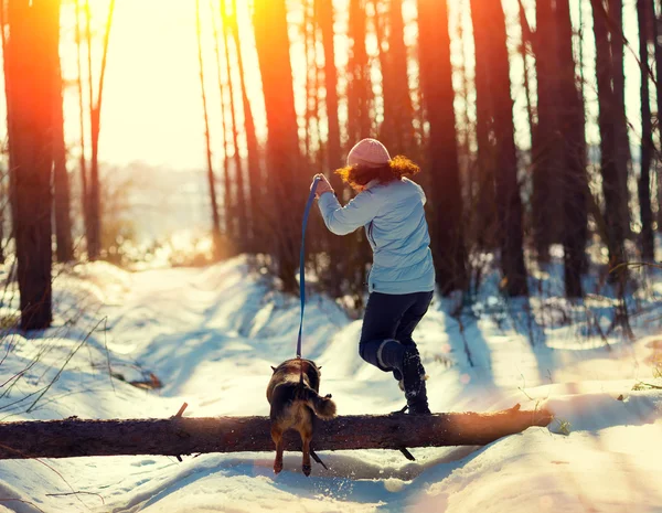 Giovane donna con cane che salta sopra un tronco — Foto Stock