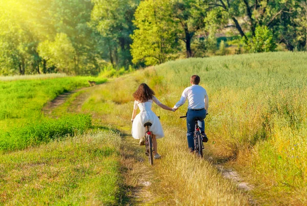 Fiatal menyasszony és a vőlegény lovagolni kerékpárok a réten — Stock Fotó