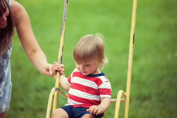 Little child swinging at playground — Stock Photo, Image