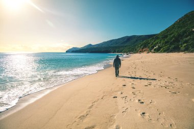 Güneşli bir günde deniz manzarası. Sahilde bir insan yürüyor. Güneşli bir günde Galapinhos plajı. Kayalık deniz manzarası. Setubal bölgesi, Atlantik Okyanusu, Portekiz