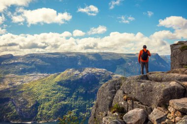 Uçurumun kenarında duran bir adam. Bulutlu bir günde güzel Lysefjord manzarası. Muhteşem Lysefjord 'un Rocky Shore' u. Norveç 'in güzel vahşi doğası
