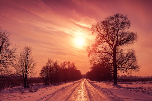 Pôr do sol sobre a estrada nevada — Fotografia de Stock