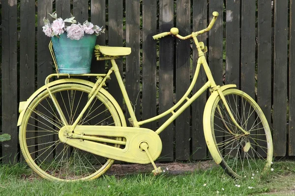 Yellow bike in front of a wooden fence — Stock Photo, Image