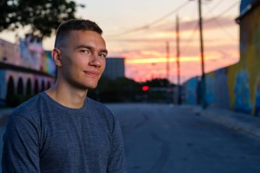 Gün batımında şehir merkezinde yakışıklı bir genç adam.