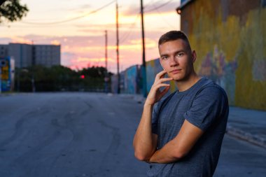 Gün batımında şehir merkezinde yakışıklı bir genç adam.
