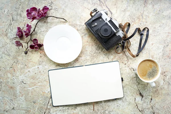 Café con orquídea, vieja cámara analógica retro, bloc de notas plano sobre mesa de mármol — Foto de Stock