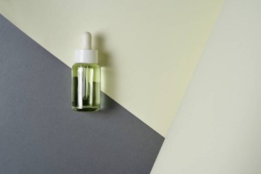 Gri ve sarı arka planda yağlı şeffaf düz bir kozmetik şişesi vardı