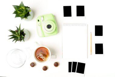 Düz uzanmış analog kamera, fotoğraflar, not defteri, kalem, çay, bardak, beyaz üzerine sulandırıcılar