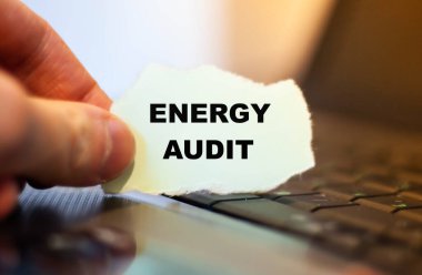 Yırtık kağıt üzerinde Klavyenin arka planına karşı ENERGY AUDIT ifadesi.