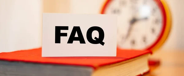 FAQ on white paper with clock background. Knowledge on remote online education.