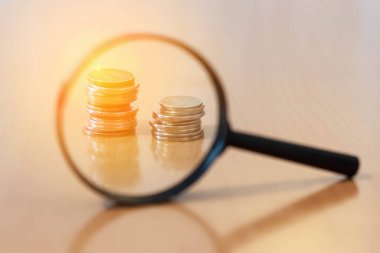 Masada büyüteçle bozuk para yığını var.