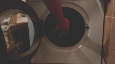 Evdeki adam çamaşır makinesinden temiz beyaz bir çarşaf çıkarıyor. Erkek temizliği ve çamaşır konsepti