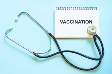 Aşılama - bir not defterinde, tavsiye olarak. Huş ağacının arka planında steteskopun yanındaki doktorun not defteri.
