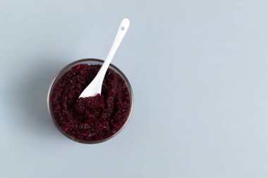 Cam kavanozda pancar reçeli ve gri bir arka planda çay kaşığı. Sağlıklı gıda konsepti. Üst Manzara. Boşluğu kopyala.