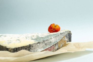 Birkaç parça bozulmuş peynir ve mavi arka planda çürük domates. Yiyecek atığı konsepti. Yakın plan. Yatay oryantasyon. Boşluğu kopyala.