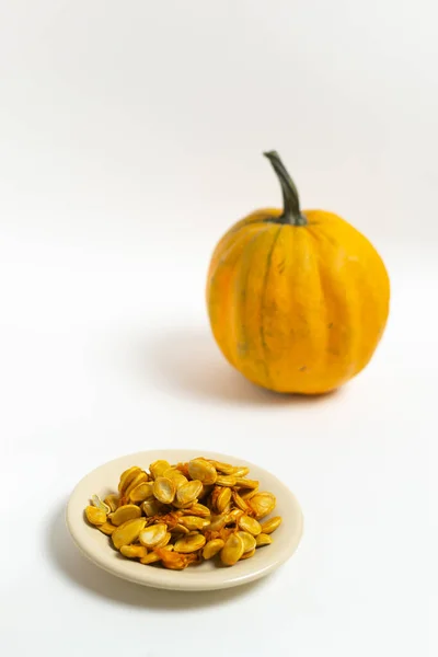 Pumpkin Seeds Saucer Orange Pumpkin White Background Autumn Harvest Selective — Stock Photo, Image