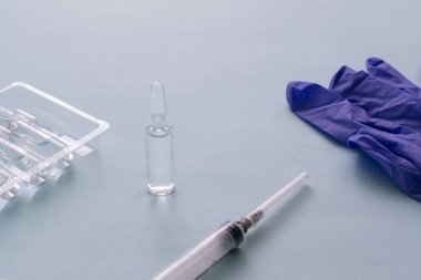 Aşı ve şırınga mavi arka planda tıbbi eldivenlerle. Aşılama. COVID-19, SARS - CoV2 aşı konsepti. Boşluğu kopyala.