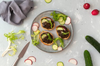 Gri bir arka planda salatalık ve turpla birlikte bir parça baget üzerinde Chia tohumu aperatifi. Üst Manzara. Yatay yönelim.