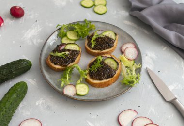 Gri arka planda gri bir tabakta malzemelerle baget dilimleri üzerinde Chia tohumu aperatifi. Yatay yönelim.