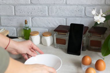 Çevrimiçi yemek kursları. Akıllı telefon ev mutfağında, ürünlerin arasında. Yemek dersi, bir kadın yemek hazırlar. Boşluğu kopyala.