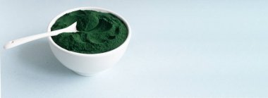 Beyaz bir kasede mavi arka planda bir çay kaşığı ve metin için yeri olan bir çay kaşığı bulunan bir sancak çiçeği tozu. Sağlıklı gıda konsepti. Yatay yönelim.