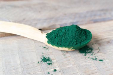 Ahşap arka planda köy kaşık spirulina tozu. Sağlıklı gıda konsepti. Yatay oryantasyon. Boşluğu kopyala.