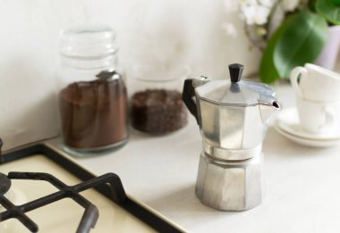 Ev mutfağında kahve yapma fikri. Bir gayzer kahve makinesi kahve kutuları ve espresso bardaklarının yanında. Yatay yönelim. 