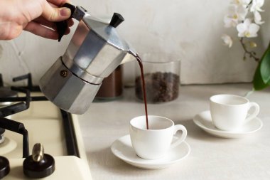 Kahve gayzer kahve makinesinden espresso bardağına dökülüyor. Evde kahve yapma konsepti. Yatay yönelim. 