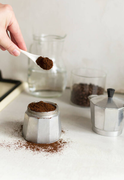 Процесс приготовления кофе дома. Кофе наливают в гейзер кофеварка на домашней кухне. Вертикальная ориентация. 