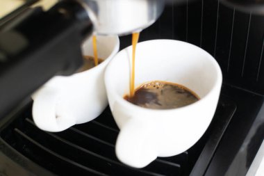 Kahve makinesi bir espresso hazırlıyor. Beyaz bir kaba doldurulmuş, hoş kokulu bir içecek. Ev yapımı kahve yapma konsepti. Yatay oryantasyon. Yakın plan.. 