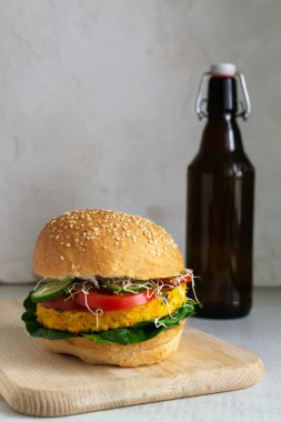 Vejetaryen burger, nohut, mercovi, soğan ve arkaplanda bira şişesi olan sarımsaklı pirzola. Vejetaryen gıda konsepti. Dikey yönelim. 