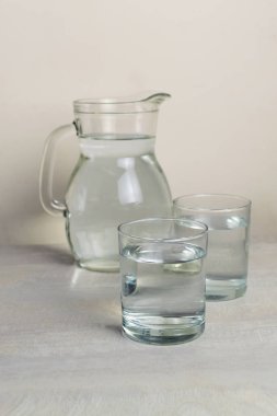 Masada iki bardak ve bir bardak temiz su var. Sağlıklı beslenme konsepti. Dikey yönelim.
