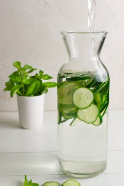 Sürahiye su dökülüyor. Salatalık, nane filizi ve detoks içeceği katılmış taze su. Sağlık, spor, sağlıklı gıda konsepti..