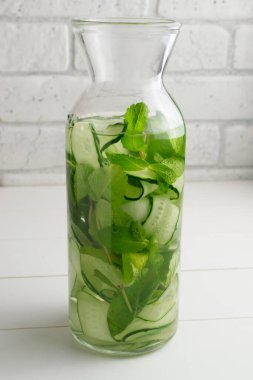 Sürahiye su dökülüyor. Salatalık, nane filizi ve detoks içeceği katılmış taze su. Sağlık, spor, sağlıklı gıda konsepti..