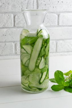 Sürahiye su dökülüyor. Salatalık, nane filizi ve detoks içeceği katılmış taze su. Sağlık, spor, sağlıklı gıda konsepti..