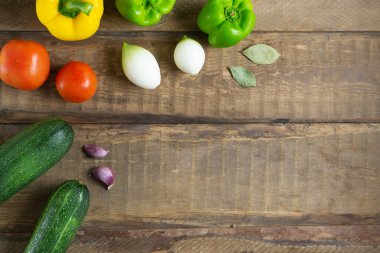 Ahşap arka planda taze sebzeler. Üst Manzara. Kabak, domates, sarı ve yeşil biber, soğan, sarımsak. Vejetaryen gıda konsepti. Boşluğu kopyala.