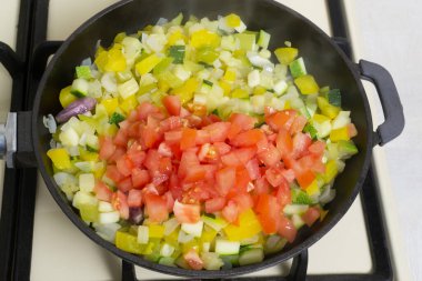 İnce doğranmış domatesler, düşük ısıda pişirilmiş kabağa, sarı ve yeşil biberlere ve dökme demir tavaya eklenir. İspanyol mutfağı konsepti. Pisto manchego..