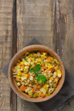 Ahşap arka planda maydanozlu seramik bir kasede rengarenk sebzeler. İspanyol mutfağı konsepti. Pisto manchego..