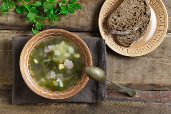 木製の背景にスプーンとパンのスライスと緑のボルシチのボウル 夏の食事スープ トップ表示 — ストック写真
