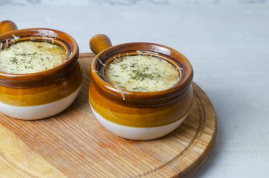 Fransız soğan çorbası pişirme süreci. Çorba ve erimiş peynirli iki seramik kase. Geleneksel mutfak konsepti. Yatay oryantasyon. Seçici odak.