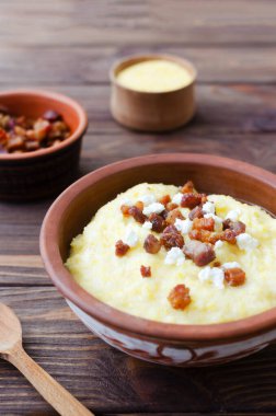Klasik banosh, bryndza ve pastırma dilimleri ile dekoratif seramik kasede ahşap bir masada. Geleneksel Ukrayna yemeği mısır unundan yapılır. Geleneksel mutfak konsepti. Seçici odaklanma. Boşluğu kopyala