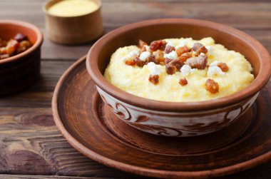 Dekoratif seramik kasede domuz pastırması dilimleri ve bryndza ile klasik banosh. Geleneksel mısır unu yemeği, rahat ve rahat servis edilir. Seçici odak