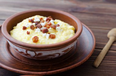 Klasik banosh, bryndza ve pastırma dilimleri ile dekoratif seramik kasede ahşap bir masada. Geleneksel Ukrayna yemeği mısır unundan yapılır. Geleneksel mutfak konsepti. Seçici odaklanma. Boşluğu kopyala