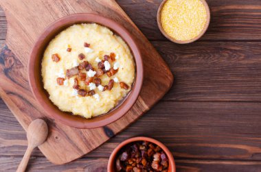 Klasik banosh, bryndza ve pastırma dilimleri ile dekoratif seramik kasede ahşap bir masada. Geleneksel Ukrayna yemeği mısır unundan yapılır. Seçici odaklanma. Üst Manzara. Boşluğu kopyala