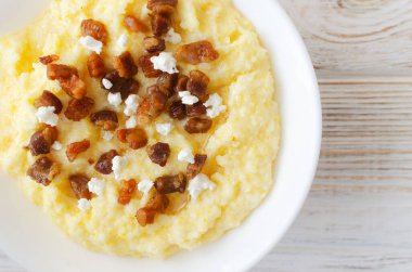Geleneksel Hutsul banosh, bryndza ve ahşap bir masada beyaz bir kase içinde çıtır çıtır çıtır çıtır. Otantik Ukrayna mutfağı sıcak ve sade bir havası var. Seçici odaklanma. Üst Manzara. Boşluğu kopyala