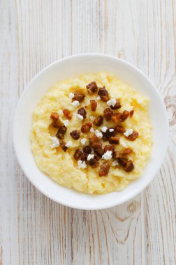 Geleneksel Hutsul banosh, bryndza ve ahşap bir masada beyaz bir kase içinde çıtır çıtır çıtır çıtır. Otantik Ukrayna mutfağı sıcak ve sade bir havası var. Seçici odaklanma. Üst görünüm.