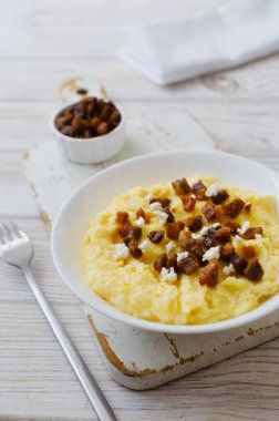 Geleneksel Hutsul banosh, bryndza ve ahşap bir masada beyaz bir kase içinde çıtır çıtır çıtır çıtır. Otantik Ukrayna mutfağı sıcak ve sade bir havası var. Seçici odaklanma. Boşluğu kopyala