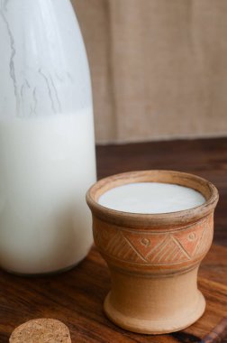 Taze kefir ile kil bardak, cam bir kavanozun yanına yerleştirilmiş, mantar tıpası ile kapatılmış. Kültürel miras, zanaatkar gıda uygulamaları ve doğal yaşam tarzı. Mayalanmış süt ürünleri kavramları