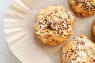 İçinde susam, keten ve balkabağı ve kağıt üzerine serpiştirilmiş ev yapımı mercimek çörekleri. Sağlıklı vejetaryen pişirme konsepti, doğal dokular ve minimum arkaplan. Üst görünüm