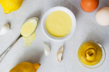 Beyaz bir kasede açık gri arka planda malzemelerle kokulu sarımsak sosu. Çeşitli yemekler için Akdeniz sosu. Yatay oryantasyon. Üst görünüm